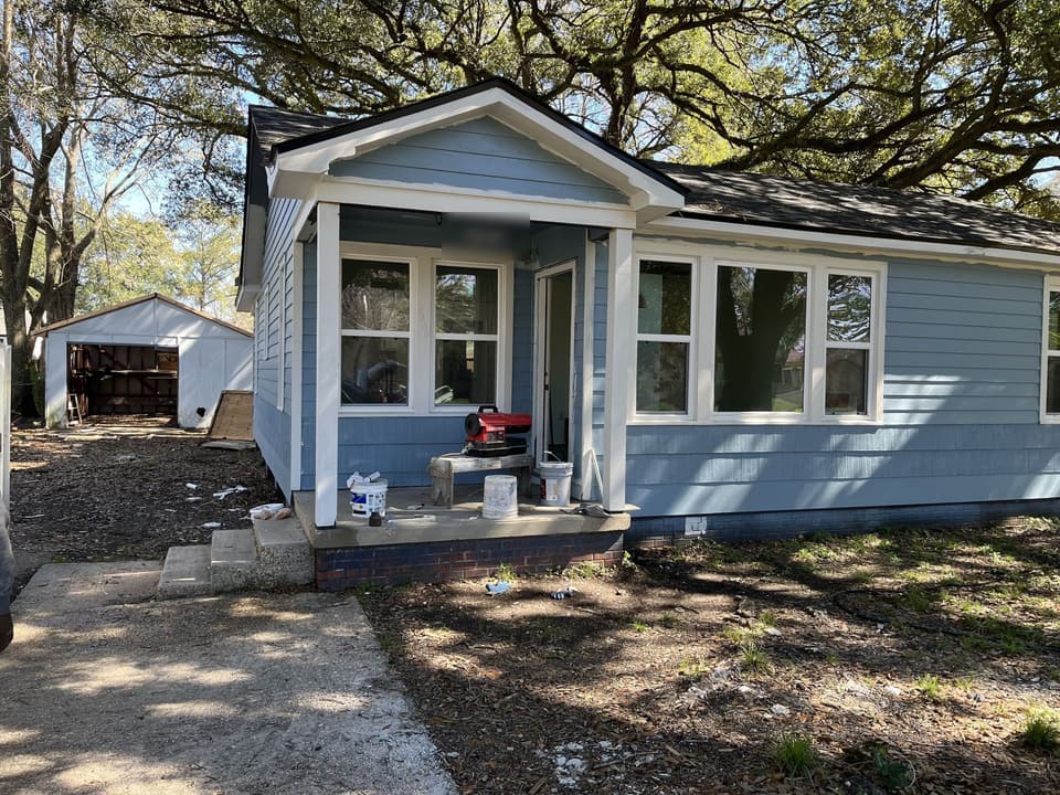 Same house after remodel, with new blue siding, new windows and a rebuilt front porch