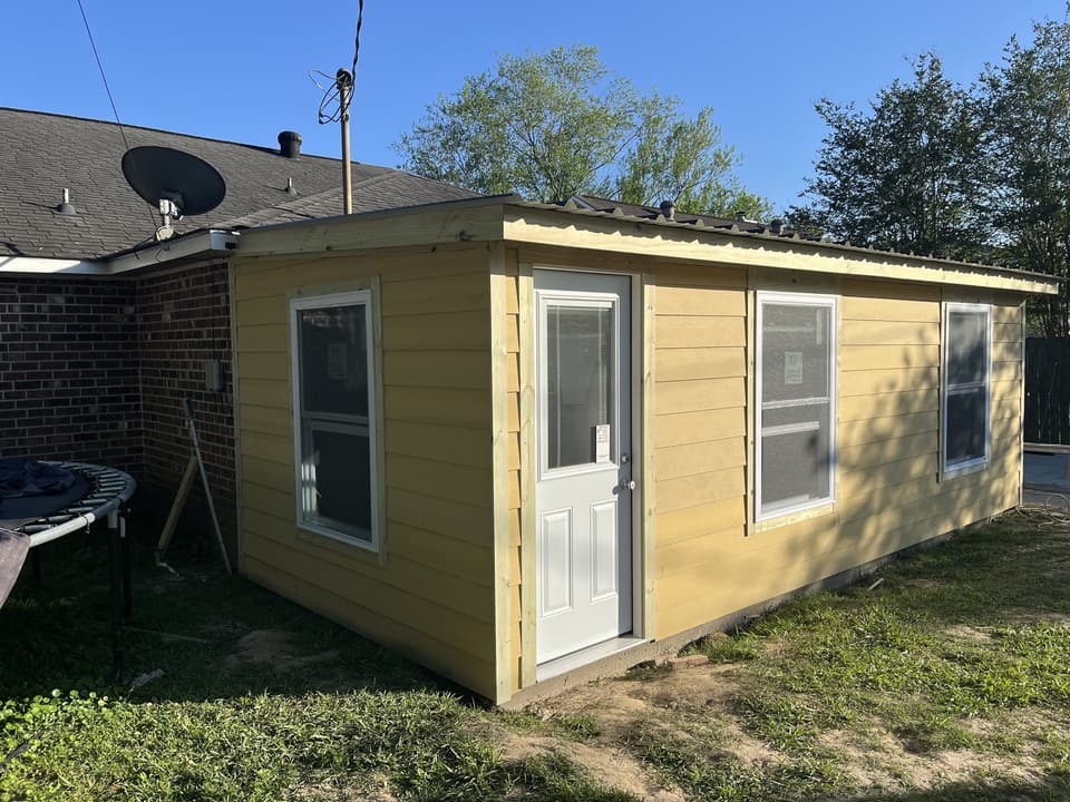 Finished room addition with yellow siding, windows and an entry door