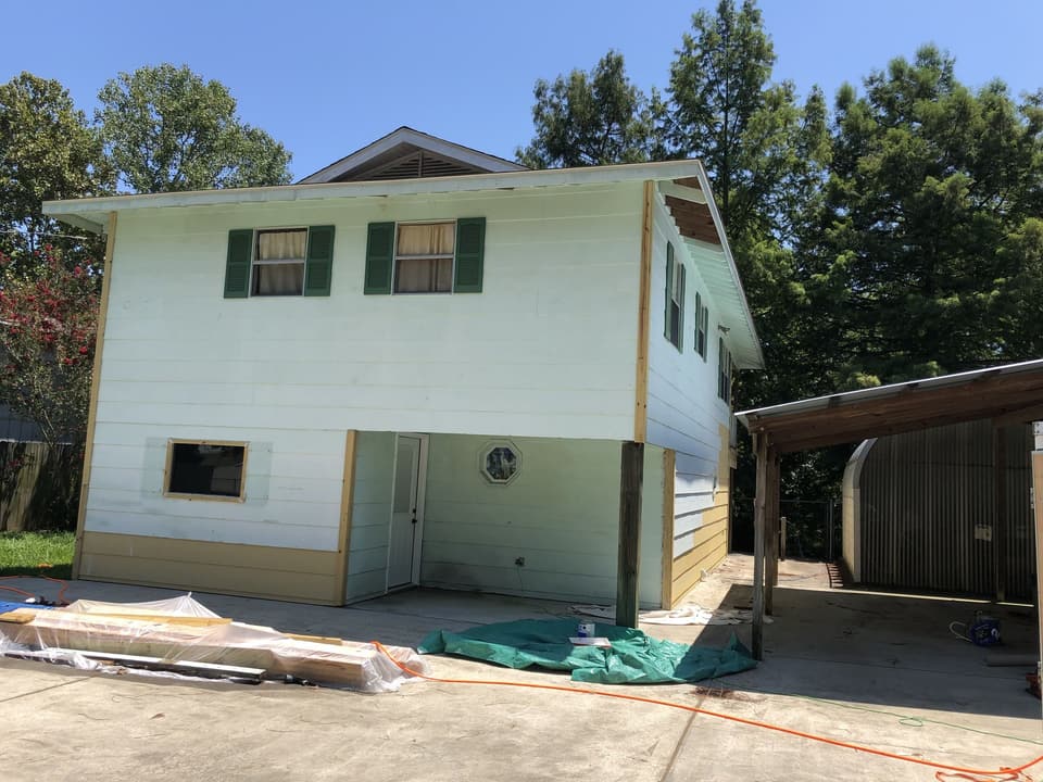 Two-story house with worn white siding before the re-side